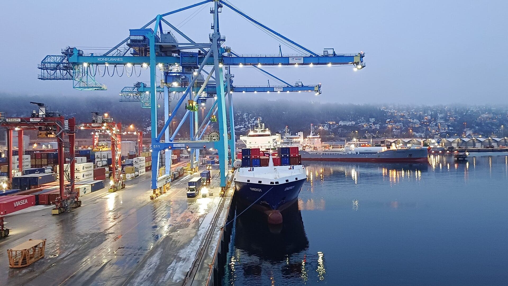 Container cranes and a moored cargo ship at a terminal at dusk