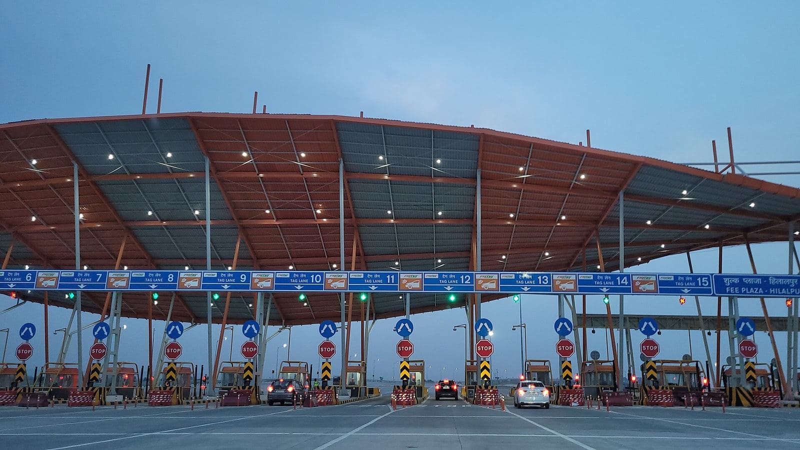 A multi-lane highway toll plaza under a wide canopy